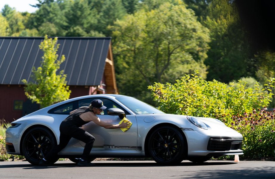 Technician hand drying a silver Porsche 911